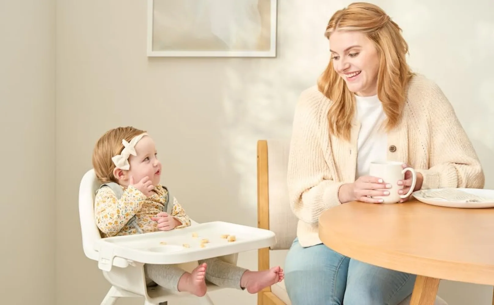 Girl eating snack in Regalo Baby Basics High Chair 3600 next to her mom 